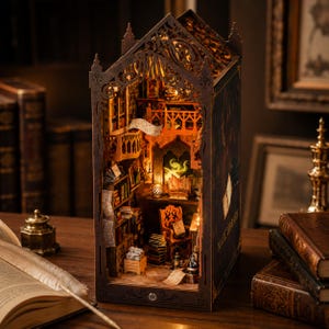 May include: A dark brown wooden book nook insert featuring a miniature library scene with intricate laser-cut details, a balcony, a chair, stacks of books, and warm internal lighting. The side panel displays the text Magic Library in gold lettering.