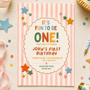 Puede incluir: Una tarjeta de invitación de cumpleaños rectangular con rayas verticales rosas y blancas, con un centro festoneado blanco con el texto IT'S FUN TO BE ONE! JOHN'S FIRST BIRTHDAY, fecha, hora, lugar y detalles de RSVP, rodeada de estrellas de papel de colores.