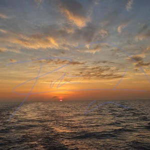May include: A sunset over the ocean with a vibrant orange sun dipping below the horizon. The sky is filled with wispy, golden-yellow clouds against a soft blue backdrop. The dark water reflects the warm light, creating a calm, expansive scene.
