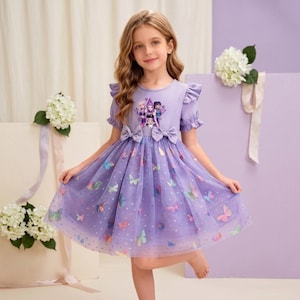 May include: A light purple dress with short ruffled sleeves and a ribbed bodice featuring a graphic print of three characters inside a star. The skirt is made of layered tulle with a pattern of colorful butterflies and small dots, accented by two bows.