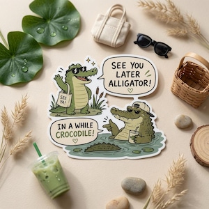 May include: A die-cut sticker featuring two green alligators with speech bubbles. One alligator wears sunglasses and carries a tote bag labeled SEE YA, while the other wears a baseball cap in water. The text reads SEE YOU LATER ALLIGATOR and IN A WHILE CROCODILE.
