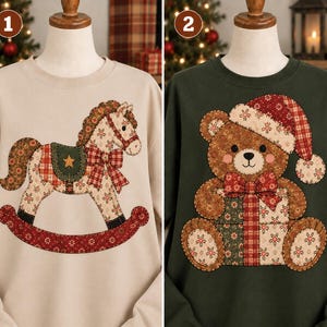 May include: Two crewneck sweatshirts displayed on mannequins. The first is beige with a rocking horse applique featuring floral and plaid patterns. The second is dark green with a teddy bear applique wearing a Santa hat and holding a gift.