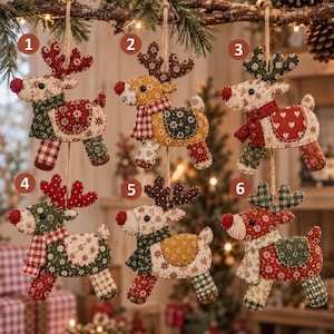 May include: Six fabric reindeer ornaments hanging by twine. Each reindeer features a unique combination of patterned textiles including red, green, white, and brown colors. The designs incorporate motifs like hearts, flowers, and plaid, with stitched details.
