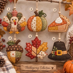 May include: Six fabric Thanksgiving ornaments hanging from twine with wooden beads. The set includes a turkey, pumpkin, slice of pie, acorn, maple leaf, and pilgrim hat, all featuring patchwork patterns in autumn colors and a Thanksgiving Collection sign.
