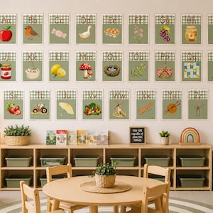 May include: A set of twenty-six educational alphabet wall posters, each featuring a letter from A to Z on a sage green gingham background with a corresponding illustration, displayed in a grid arrangement above a wooden classroom storage unit.