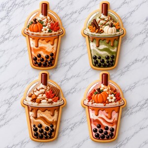 May include: Four decorative bubble tea shaped ornaments featuring autumn themes. Each cup has a brown straw, whipped cream, and toppings like pumpkins, maple leaves, and flowers. The drinks display swirling colors of orange, green, and pink with black boba pearls at the base, all encased in a clear plastic dome lid.