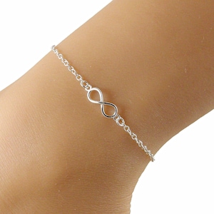 May include: A delicate silver anklet with an infinity symbol charm. The anklet is made of a fine chain, with the infinity symbol as the focal point. The jewellery is designed to be worn around the ankle.