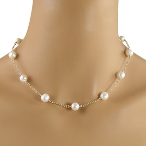 Może przedstawiać: Delikatny złoty łańcuszek z białymi perłami. Naszyjnik ma prosty design z równomiernie rozmieszczonymi perłami.