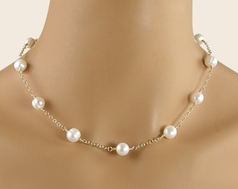 Puede incluir: Un collar delicado que presenta una serie de perlas blancas redondas espaciadas uniformemente a lo largo de una fina cadena de metal dorado. Las perlas están unidas individualmente por segmentos de cadena, creando un diseño simple y uniforme.