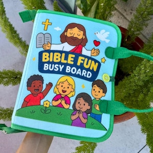 May include: A light blue felt busy board with green trim and handles, featuring the text BIBLE FUN BUSY BOARD. The cover displays a cartoon illustration of a figure with a beard, a white dove, and four children standing on a green hill.
