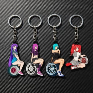 Peut inclure: Quatre porte-clés en métal représentant des personnages de style anime assis sur des roues de voiture. Les personnages ont des cheveux violets, magenta, bleu sarcelle et rouges, vêtus de tenues décontractées. Chaque porte-clés inclut un anneau.