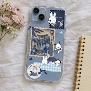Könnte beinhalten: Eine transparente Handyhülle mit hellblauem Hintergrund und verschiedenen Aufklebern, darunter eine japanische Briefmarke mit einem Torii-Tor, Miffy-Figuren, Pochacco und ein blauer Vichy-Karo-Streifen mit kleinen dunkelblauen Schleifen.
