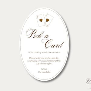K&ouml;nnte beinhalten: Ein ovales Schild mit wei&szlig;em Hintergrund und dunkelbraunem Text. Oben sind zwei Spielkarten abgebildet, eine Herz-Dame und ein Herz-K&ouml;nig. Der Text lautet: Pick a Card, We're creating a deck of memories. Please write your wishes and sign your name.