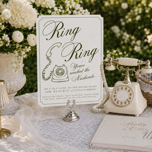 May include: A white rectangular sign with dark green text reading Ring Ring You've reached the Naslands... We can't come to the phone right now, we're busy getting married! Pick up the phone, leave your well wishes after the tone, then hang up.