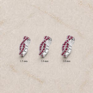 May include: Three silver-toned rings featuring a twisted design set with small pink stones. The rings are labeled with sizes 1.5 mm, 1.8 mm, and 2.0 mm, indicating their respective widths. Each ring displays a continuous, interwoven metal band.