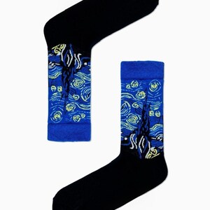 May include: A pair of crew socks featuring a black toe, heel, and cuff, with a mid-section displaying a blue, yellow, and white swirling pattern inspired by The Starry Night. The design includes yellow circular motifs and dark blue cypress shapes.