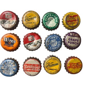May include: A collection of twelve vintage bottle caps with various brand names and designs. The caps feature a range of colors, including red, orange, yellow, green, blue, and purple. Some caps have text such as "Vernor's Ginger Ale" and "Dr. Pepper."
