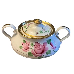Pu&ograve; includere: Zuccheriera in ceramica bianca con coperchio, con rose rosa e foglie verdi dipinte a mano. I bordi e le maniglie sono dorati. La ciotola ha due manici e un pomello dorato sul coperchio.
