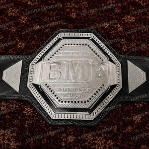 Può includere: Una cintura da campionato in pelle nera con una grande placca metallica ottagonale color argento. La placca centrale è incisa con il testo BMF, BADDEST, MOTHER FUCKER e MCMKC111. Due piccoli accenti triangolari argentati sono sulla cinghia.