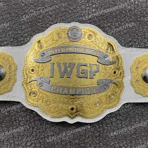 Può includere: Una cintura da campionato in pelle bianca con una grande piastra centrale dorata e ornata con il testo IWGP INTERCONTINENTAL CHAMPION inciso in argento. Quattro piastre laterali circolari dorate sono fissate al cinturino in pelle bianca.