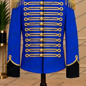 May include: A bright blue military-style jacket featuring gold braided cord detailing, gold-tone buttons, black cuffs, and a black mandarin collar. The shoulders are accented with gold fringe epaulets, and the front displays horizontal gold trim.