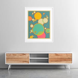 a vibrant abstract painting hanging on a white wall above a white entertainment unit with wooden drawers.