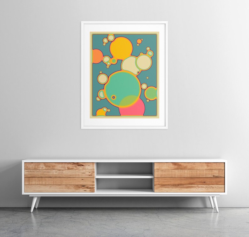 a vibrant abstract painting hanging on a white wall above a white entertainment unit with wooden drawers.