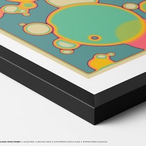 The image is a framed artwork featuring abstract, colorful shapes and patterns, including circles, ovals, and other organic forms, set against a blue and green background.