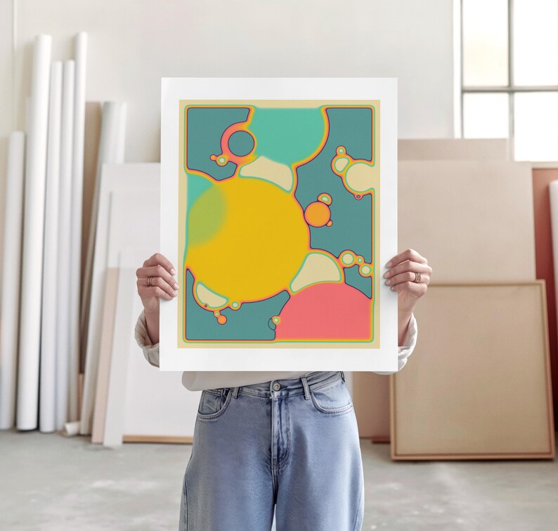 A person is holding up a colorful abstract painting in an art studio.