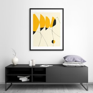 a modern black entertainment center with a framed abstract art piece hanging above it. The entertainment center has a sleek design and appears to be well-organized.