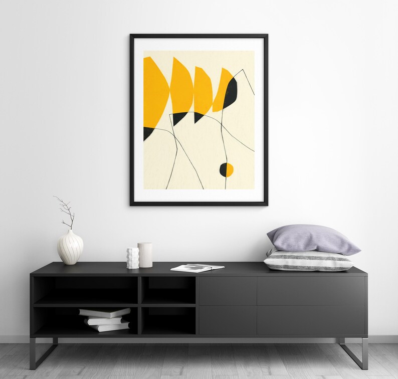 a modern black entertainment center with a framed abstract art piece hanging above it. The entertainment center has a sleek design and appears to be well-organized.