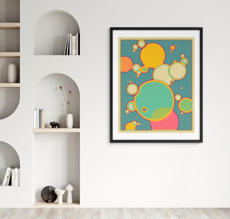a vibrant abstract painting with a mix of yellow, green, and pink circles and shapes, hanging on a white wall above a shelf with decorative items.