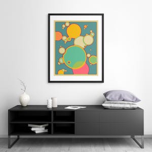a modern black entertainment center with a framed abstract art piece hanging above it. The entertainment center has a shelf with books and a vase on it.