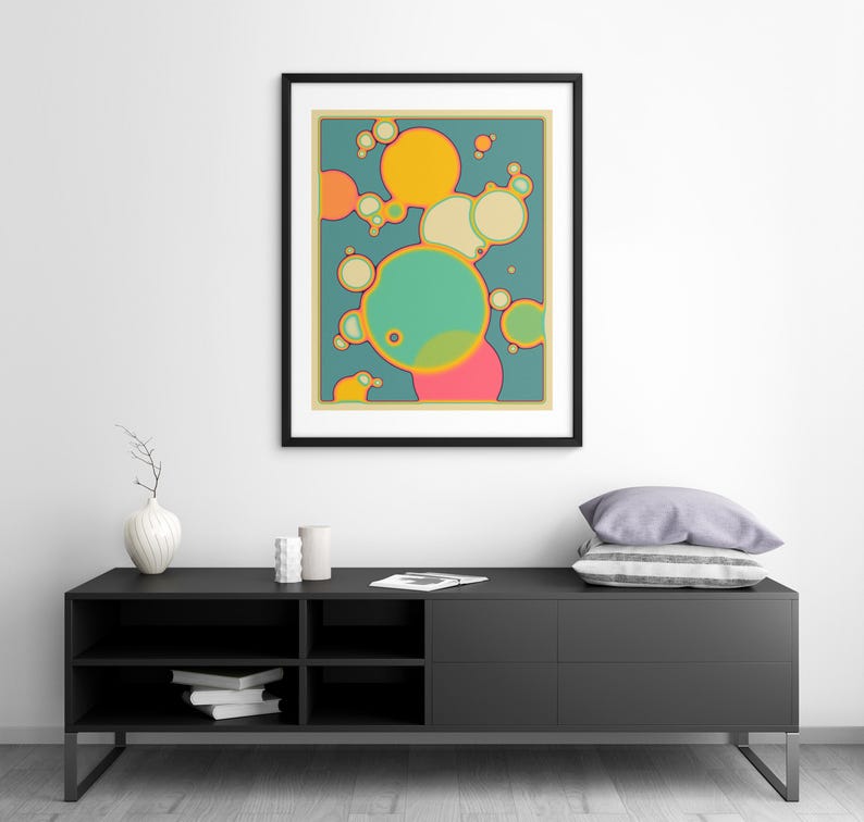 a modern black entertainment center with a framed abstract art piece hanging above it. The entertainment center has a shelf with books and a vase on it.