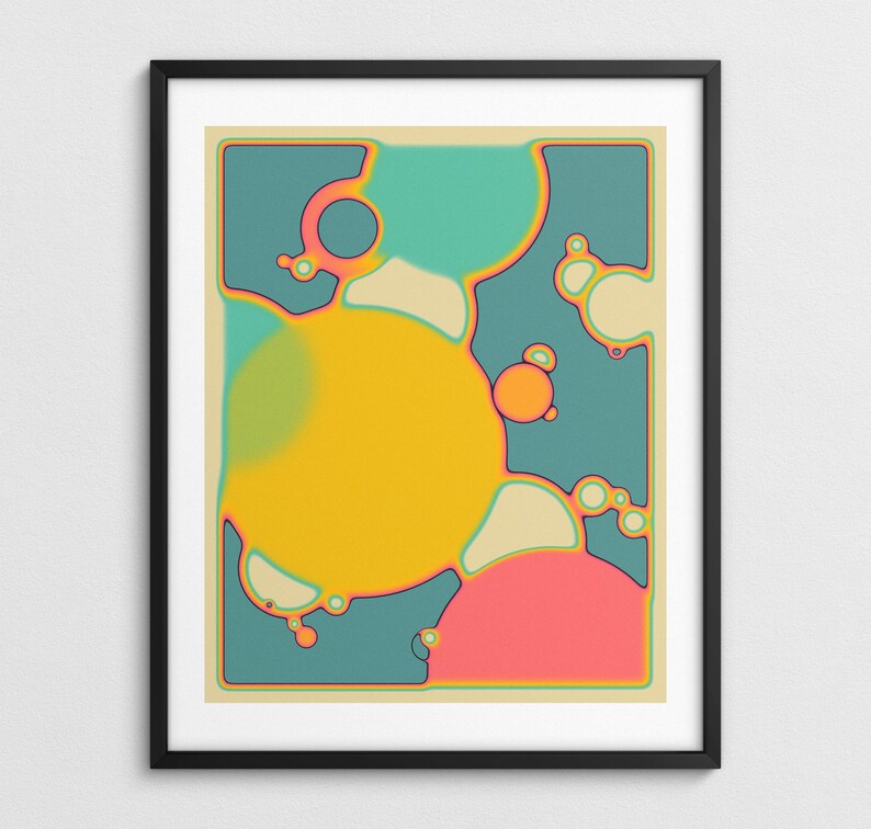 The image is a framed abstract artwork with a vibrant color scheme of yellow, pink, blue, and green. The artwork features various shapes and forms, including circles, ovals, and other organic and geometric elements, creating a visually striking and dynamic composition.