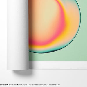 The image is a rolled canvas print featuring a vibrant abstract design with a gradient of colors, including shades of orange, pink, and green.