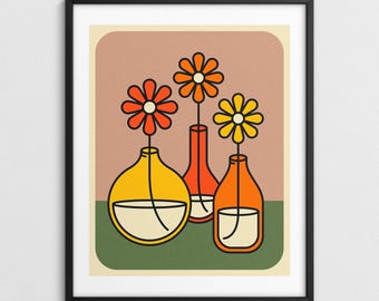 Op de afbeelding: Een ingelijste kunstdruk met drie gestileerde vazen, elk met een enkele bloem. De bloemen zijn oranje en geel, en de vazen zijn geel, oranje en amber. De achtergrond is een gedempt roze met een groene basis.