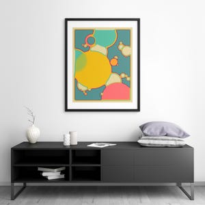a modern black entertainment center with a framed abstract art piece hanging above it. The entertainment center has a shelf with books and a vase on it.