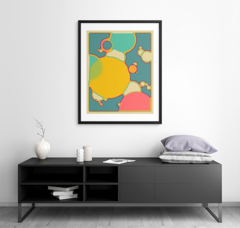a modern black entertainment center with a framed abstract art piece hanging above it. The entertainment center has a shelf with books and a vase on it.