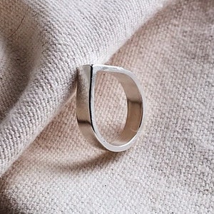 Op de afbeelding: Een zilveren ring met een unieke traanvorm. De ring is gemaakt van metaal en heeft een gladde, gepolijste afwerking.