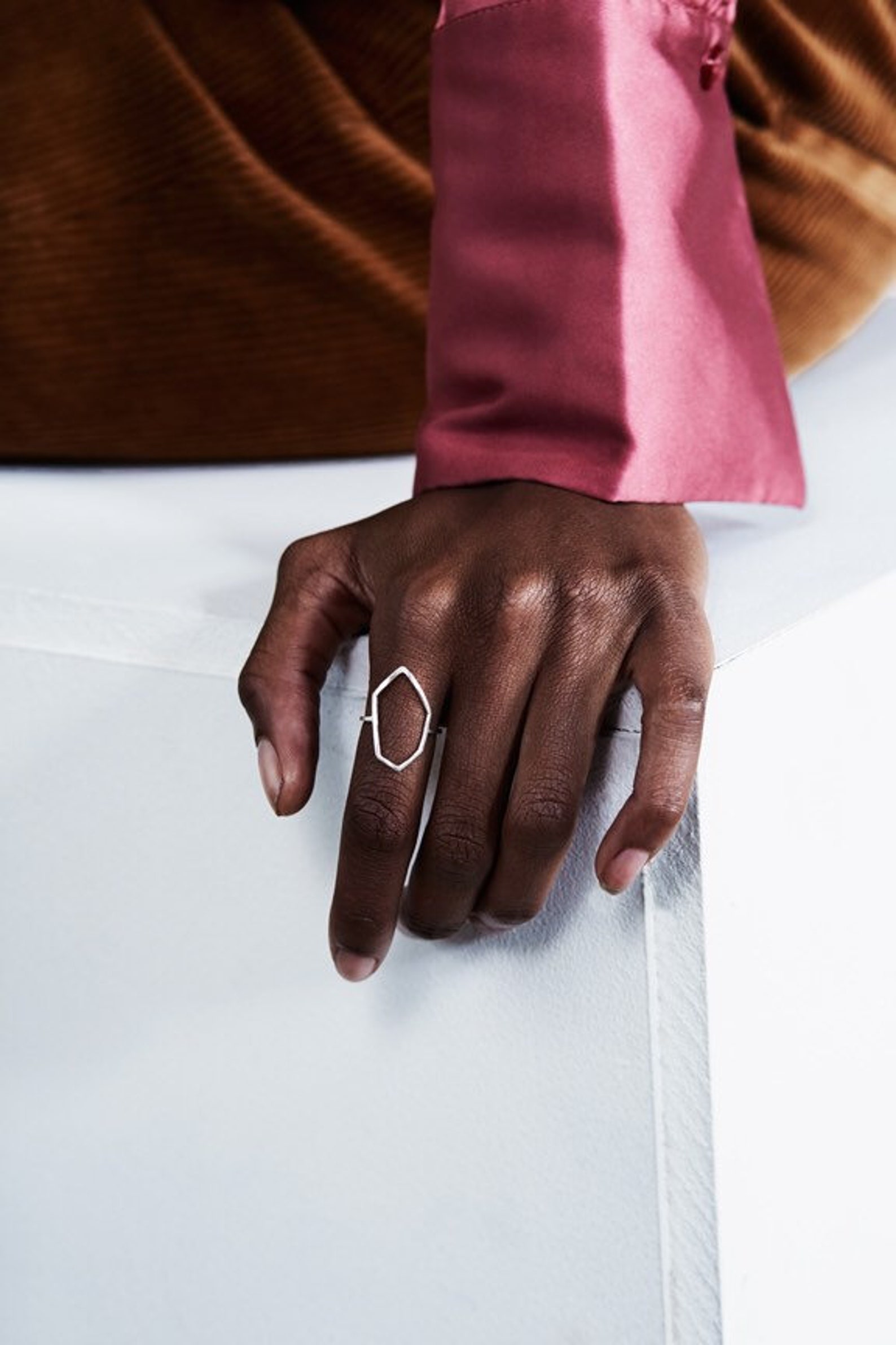 A hand wearing a handcrafted sterling silver architectural crystalline outline ring.