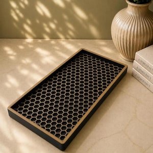 May include: A rectangular tray featuring a black base with a gold-colored honeycomb pattern overlay. The tray has a solid black outer rim and a flat surface, designed with a repeating hexagonal grid structure across the entire interior base area.