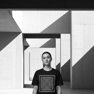 May include: A black short-sleeve t-shirt featuring a graphic of nested white squares creating an infinity tunnel effect on the chest. The text "INFINITY YOU CAN FEEL." is printed in white capital letters at the top of the image.