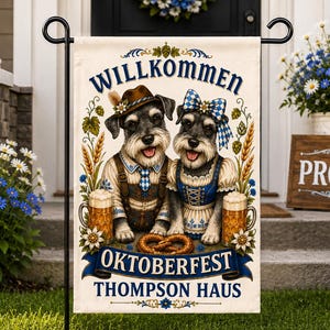 Puede incluir: Una bandera de jardín rectangular que muestra dos perros Schnauzer vestidos con trajes bávaros tradicionales, incluyendo un sombrero y un lazo a cuadros azules. El texto dice WILLKOMMEN, OKTOBERFEST y THOMPSON HAUS, junto a jarras y pretzels.