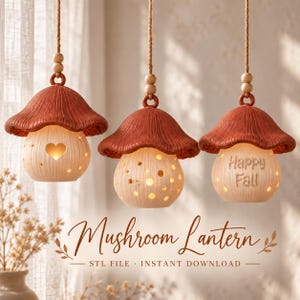 May include: Three hanging mushroom lanterns with terracotta-colored caps and cream-colored bases. The lanterns feature cutouts, including a heart shape and the text "Happy Fall" on the rightmost lantern, suspended by jute ropes with wooden beads.
