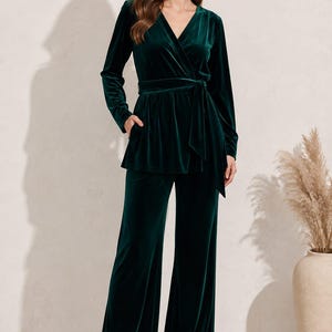 May include: A dark emerald green velvet two-piece set consisting of a long-sleeve wrap top with a tie waist and matching wide-leg trousers. The top features a V-neckline and side pockets, while the trousers have a straight, flowing silhouette.