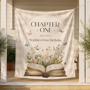 May include: A beige and white checkered fabric backdrop featuring an arched frame with the text 'CHAPTER ONE - Welcome to Sophia's First Birthday'. The design includes an open book with colorful wildflowers emerging from the pages and butterflies.