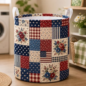 May include: A cylindrical laundry hamper featuring a quilted patchwork design in red, white, and blue. The exterior displays various patterns including floral prints, gingham checks, stars, and stripes. It has two white fabric handles at the top.