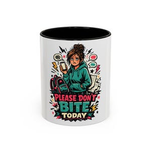 May include: A white ceramic mug with a black interior and rim, featuring a graphic illustration of a tired person in a teal hoodie holding a phone, with a backpack and the text "PLEASE DON'T BITE TODAY" in bold, colorful, stylized lettering.