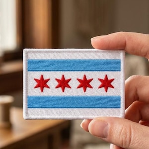 May include: A rectangular embroidered patch featuring the Chicago flag design. The patch has a white background with two horizontal light blue stripes and four bright red six-pointed stars centered in the middle white band with a white border.